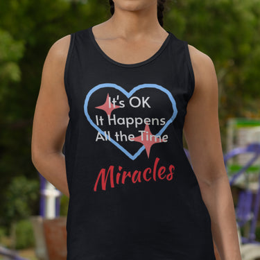 Lightweight Bella+Canvas tank top made from preshrunk cotton with “Miracles Happen” design message, “It’s OK. It Happens All the Time – Miracles,” inspirational apparel encouraging daily miracles through intimacy with God, woman in black tank top